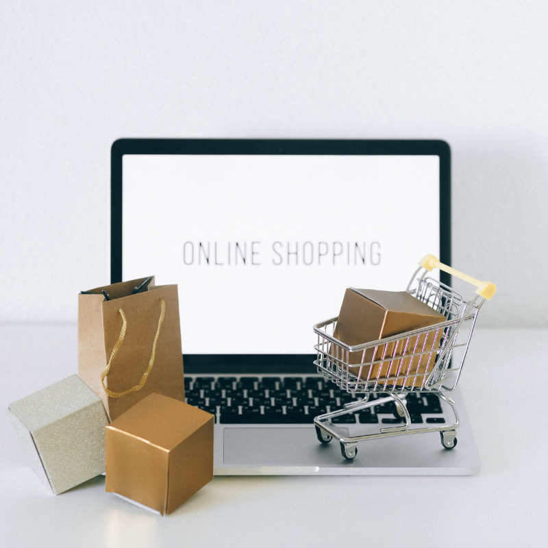 laptop with miniature shopping cart with box and bags